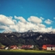 Bester Immobilienmakler Rosenheim: Ortschaft im Alpenvorland unter blauem Himmel