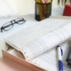 Immobilienbewertung Grasbrunn: Schreibtisch mit Unterlagen, Brille und Taschenrechner