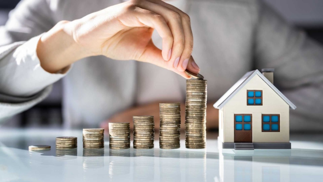 Immobilienbewertung Unterföhring: Münzstapel neben einem Hausmodell