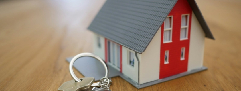 Professioneller Immobilienmakler Haidhausen: Hausmodell mit Schlüsselbund auf dem Tisch